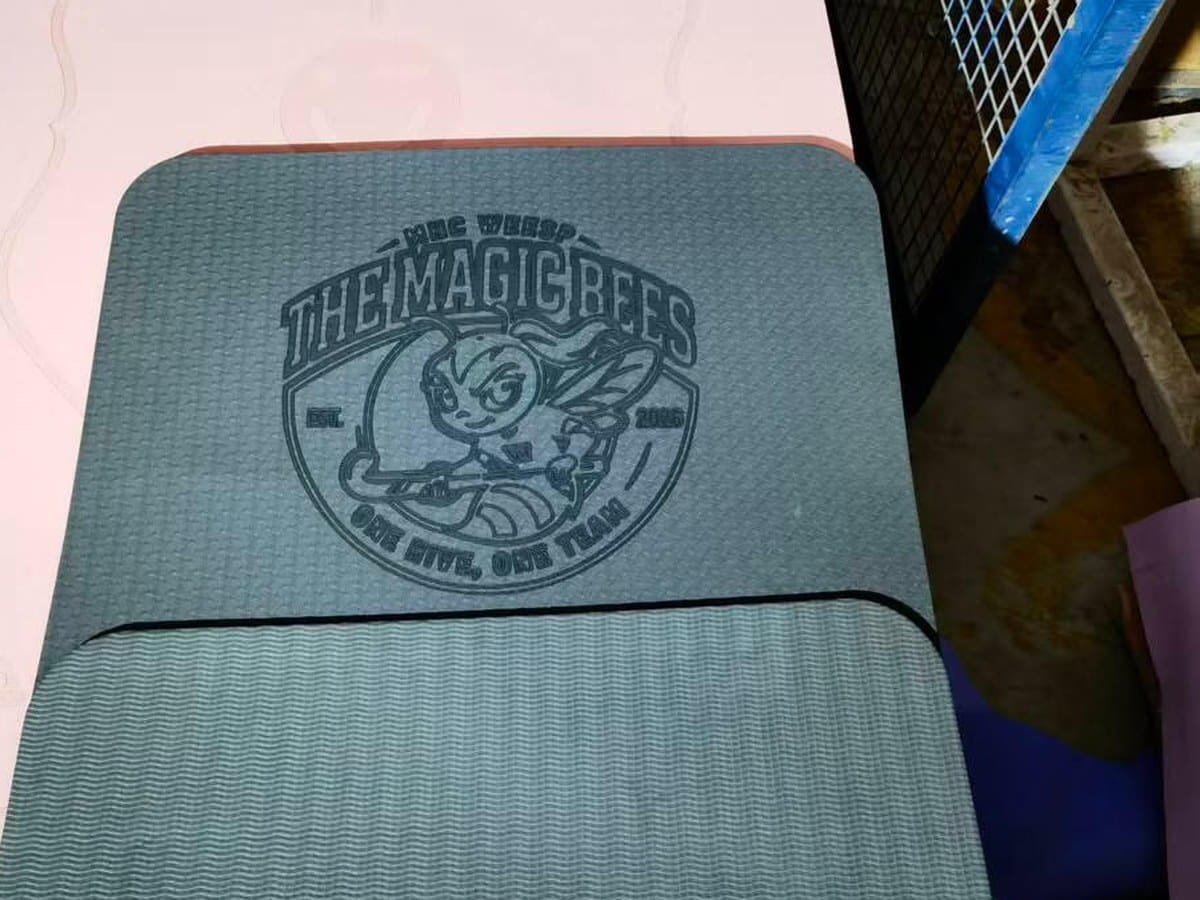 A gray sports mat with The Magic Bees logo embossed on it.